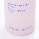 A detailed view of product text on a pink bottle reading "Lotion Démaquillante Tonique / Toning Cleansing Lotion" with "250 ml - 8.4 fl oz" visible at the bottom. A detailed view of product text on a pink bottle reading "Lotion Démaquillante Tonique / Toning Cleansing Lotion" with "250 ml - 8.4 fl oz" visible at the bottom.