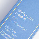 Close-up of a blue Phytomer skincare product box with gold accents showing "RÉVÉLATION LUMIÈRE SKIN LUMINATION" and French text about complexion cream for dark spots and wrinkles.