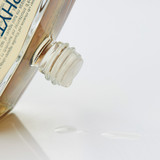 Close-up of a clear glass aftershave bottle with a threaded opening and cork-style cap.