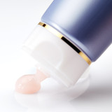 Blue skincare jar with gold accent dispensing pink cream onto white surface. Blue skincare jar with gold accent dispensing pink cream onto white surface.