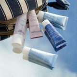 Travel size Rosee Visage Toner,  Travel Rosee Visage Gel, Travel Oligomer Well-Being Body Cream, Travel Sublime Night Balm, and Travel Expert Youth Cream spilling out of the striped cosmetic pouch.