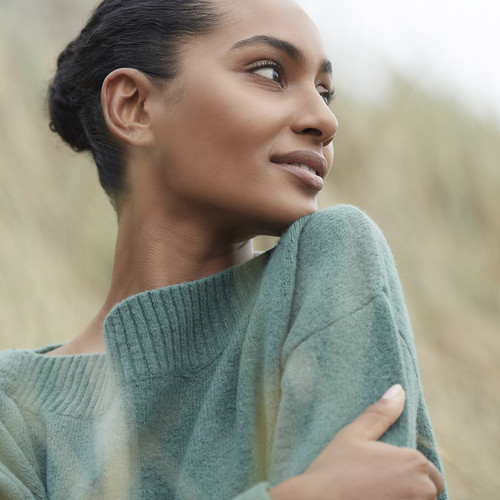 Woman in sage green sweater looking thoughtfully to the side with natural lighting. Woman in sage green sweater looking thoughtfully to the side with natural lighting.