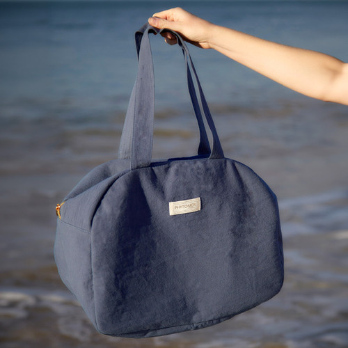 Woman holding a Phytomer Weekend Bag at the beach.
