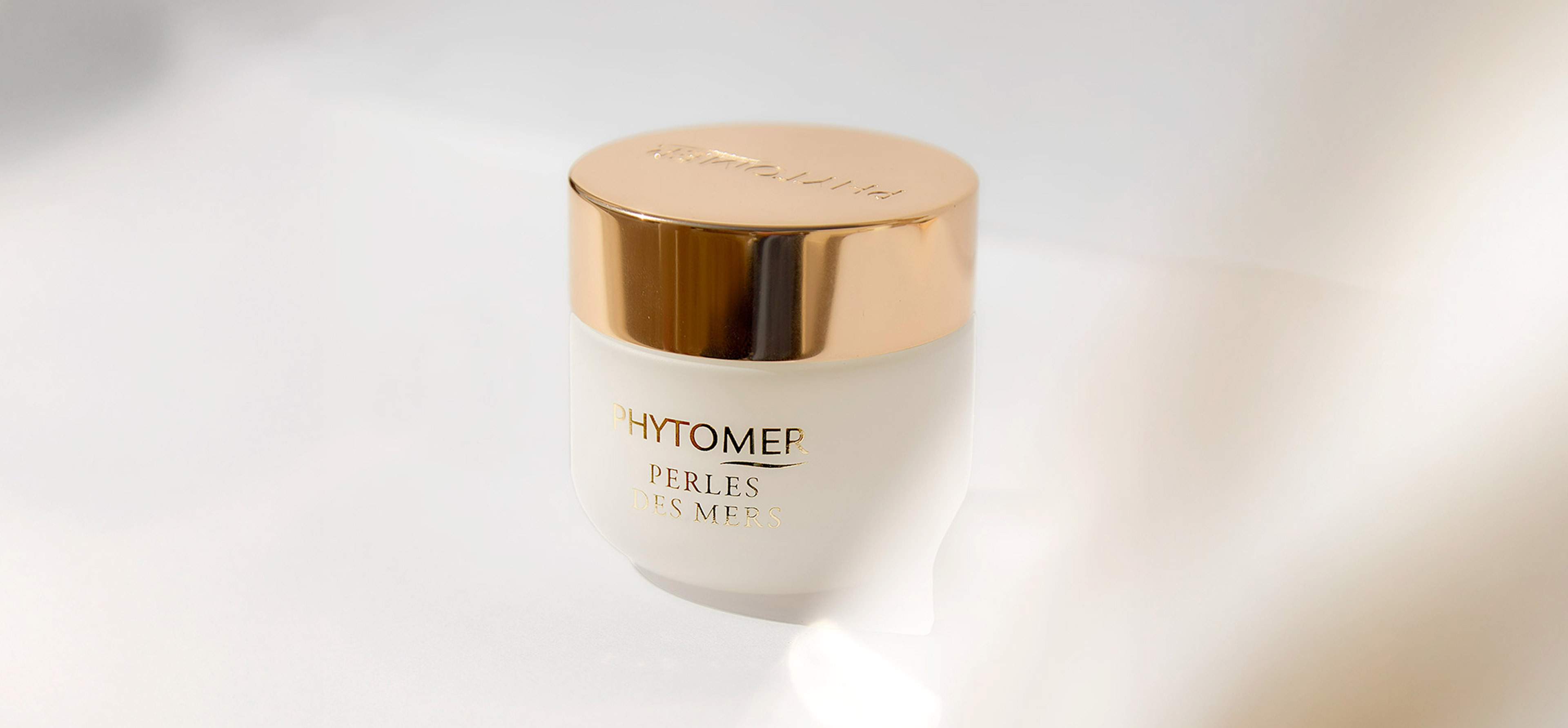 "Phytomer Perles des Mers cream jar with gold lid on white surface