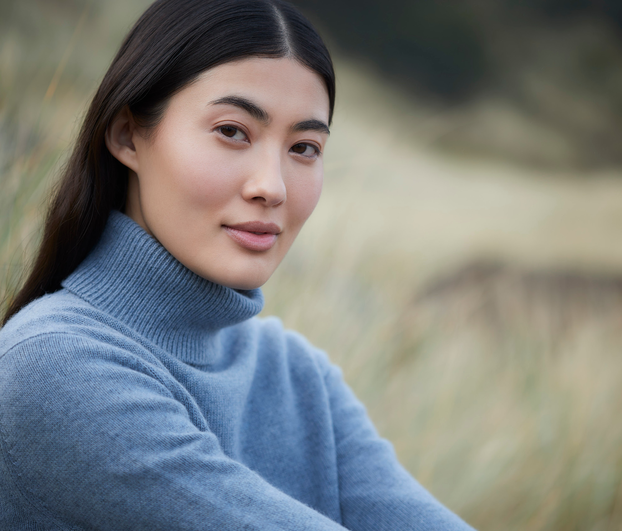 Woman looking at the camera in a blue sweater.