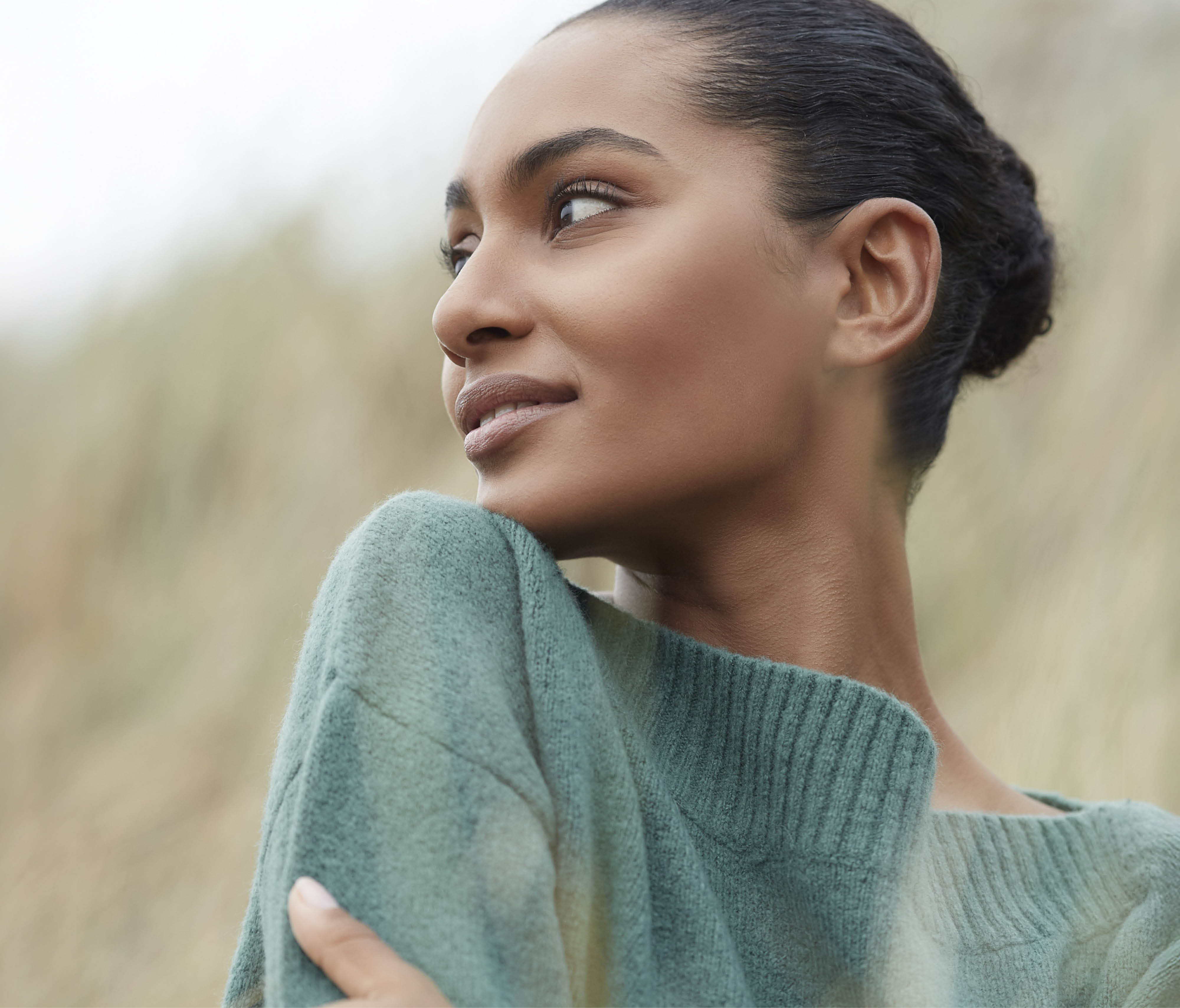 Woman in a green sweater gazing over her shoulder.