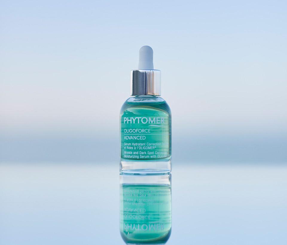 Oligoforce Advanced Serum sitting on the water with a sunset in the background. 