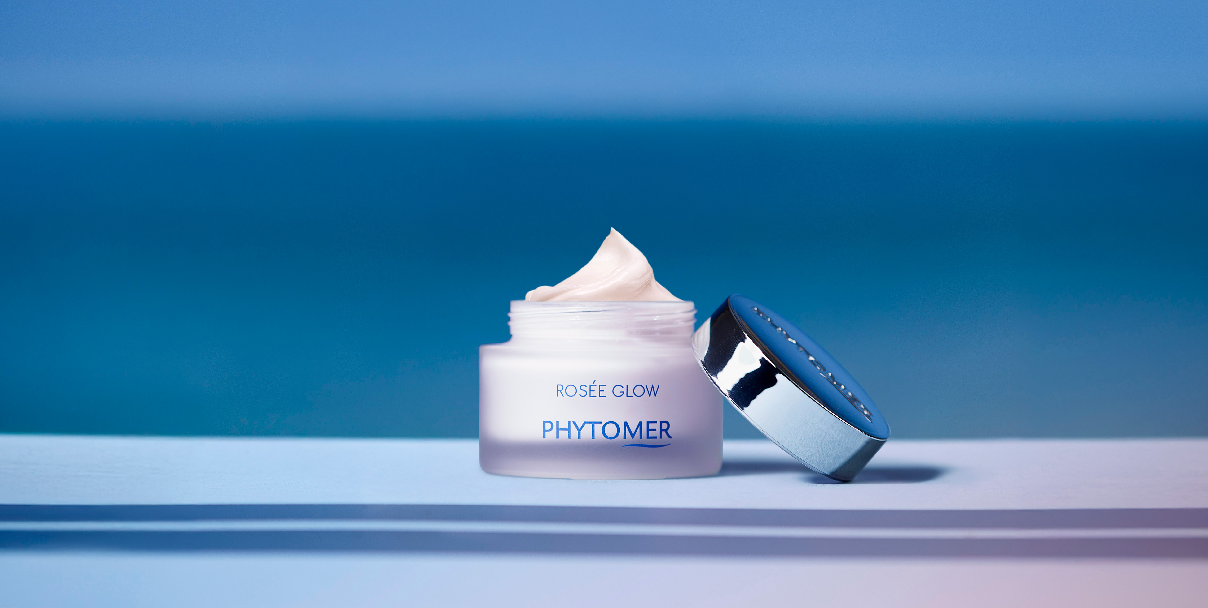 Rosee Glow Cream sitting on a table at the beach.