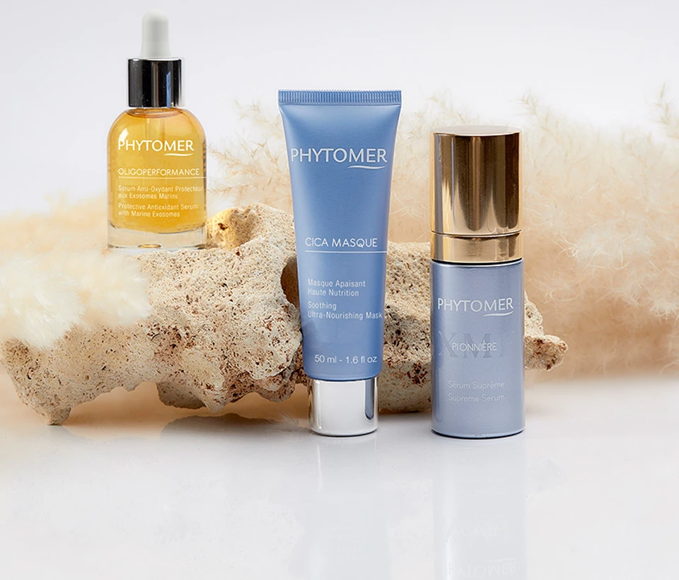 Two serums and the Cica Mask sitting on a rock. Serums pictured include the Oligoperformance Protective Antioxidant Serum with Marine Exosomes and XMF Pionniere Supreme Serum.