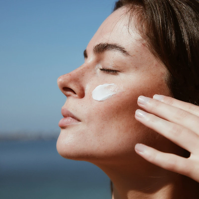 A woman swiping a portion of a phytomer day cream to her cheek.