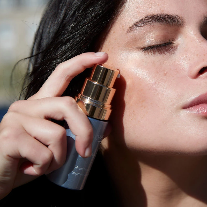 Woman with long wavy hair, gazes down at a Phytomer Hydracontinue 12H Moisturizing Flash Gel. 
