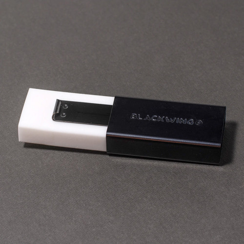 A white handheld eraser that has been extended from its black aluminum holder that has the word "BLACKWING" embossed on it.
