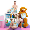 Male model standing behind shelf wearing and holding a Lunar Cub diaper towards female model with arm extended, wearing Lunar Cub sitting in front of shelf and giant teddy bear, that is also wearing Lunar Cub.