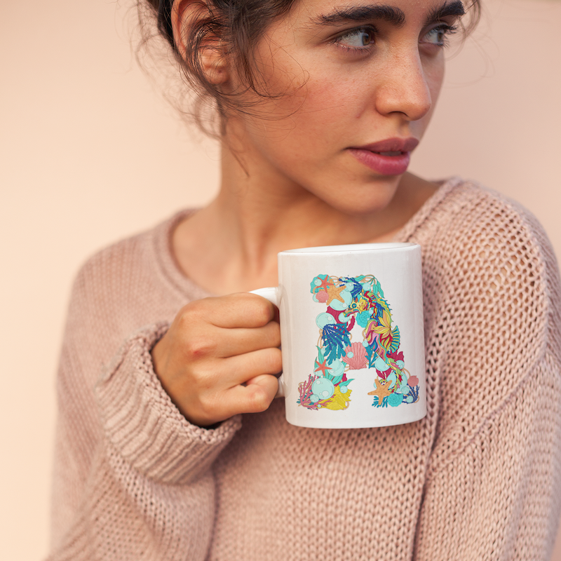 Woman looking over shoulder holding pretty initial mug, unique ocean mug, seahorse mug