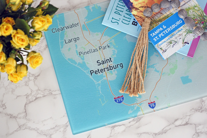 Custom map cutting board on countertop with travel books stacked on top