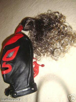 Schwarze Echtledermaske mit roten Details und lockiger brauner Perücke seitlich