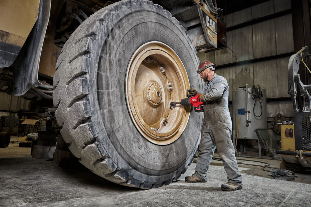 photo of an enormous CAT dumper wheel being removed by a man with a milwaukee 1" dr d-handle impact wrench