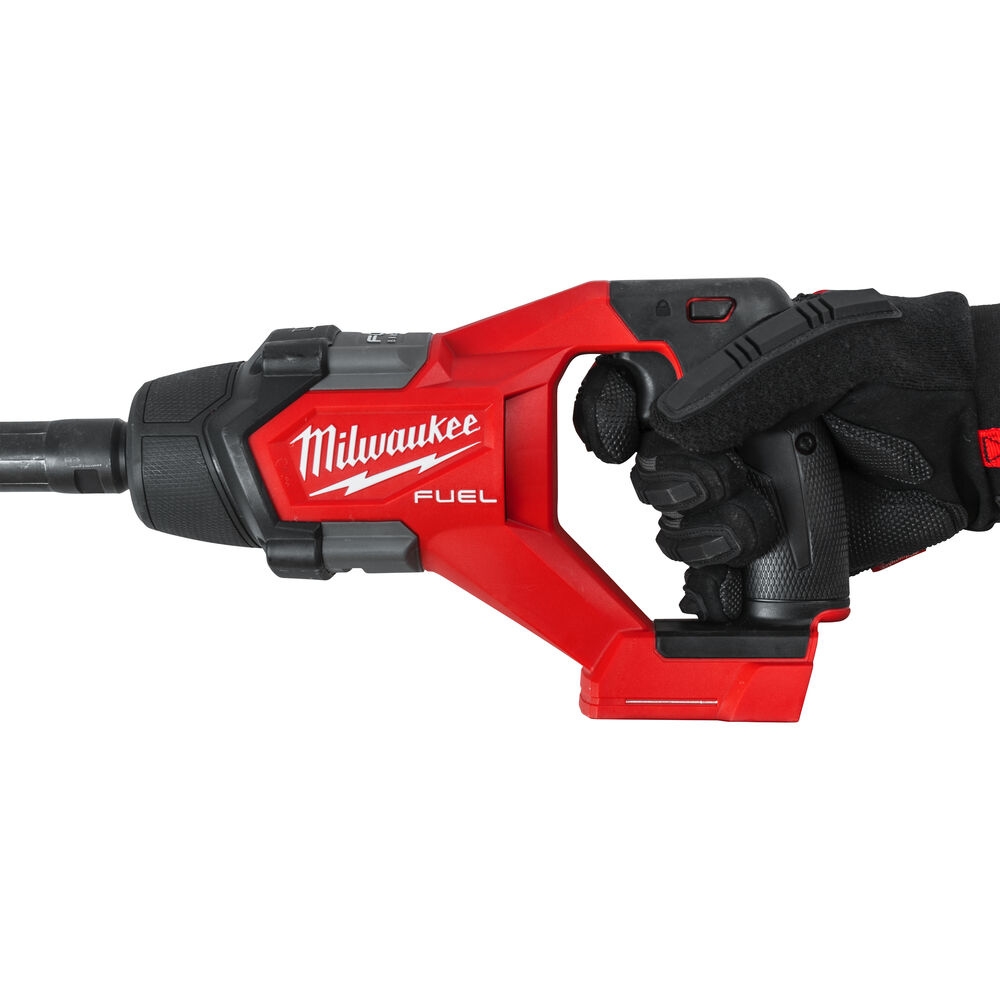 A Milwaukee glove holding the handle of a red milwaukee concrete vibrator