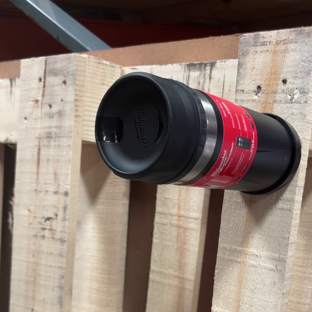 Milwaukee insulated tumbler mounted sideways onto the puck, demonstrating a secure horizontal attachment on a pallet wall.