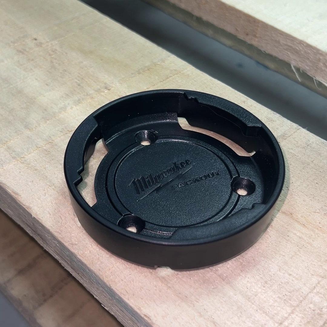 The puck with all screws removed, showing recessed mounting holes, ready to be fixed to a vertical or horizontal surface.