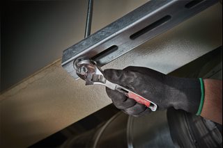 Milwaukee 150mm adjustable wrench being used on a metal component during a professional workshop or maintenance application.