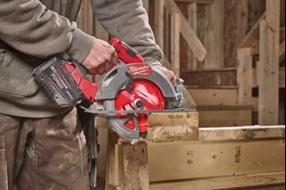 Milwaukee 165 x 20mm 24T NITRUS CARBIDE circular saw blade being used to cut wood, shown in a professional workshop or jobsite environment.