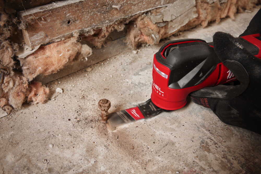 Milwaukee 35mm NITRUS CARBIDE OPEN-LOK multi-tool blade being used to cut metal in a professional jobsite environment.