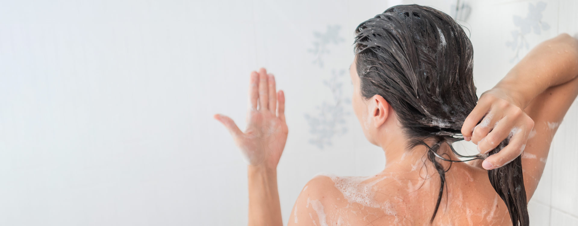 woman washing hair looking at hair fall on hand
