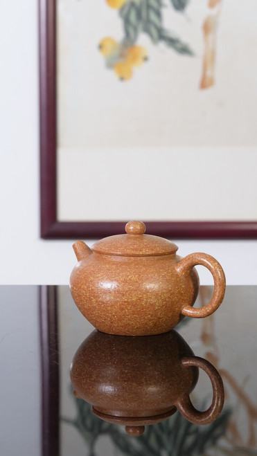 Handcrafted Osmanthus Pear Zisha teapot shot against elegant traditional Chinese scroll painting background, showing delicate golden speckled clay texture.