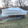 Large boat wrapped in white marine shrink wrap for long-term outdoor storage and winter protection