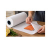 Person using a white freezer paper roll to wrap a fresh salmon fillet for food storage