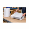 Worker wrapping electronic equipment with polyethylene foam cushioning at a warehouse packing station