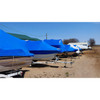 Boats protected with blue marine shrink wrap for winter storage at a marina and boat dealership