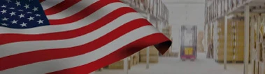 American flag waving in front of a warehouse background