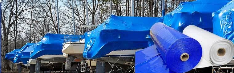 Marina yard with a line of boats wrapped in blue marine shrink wrap