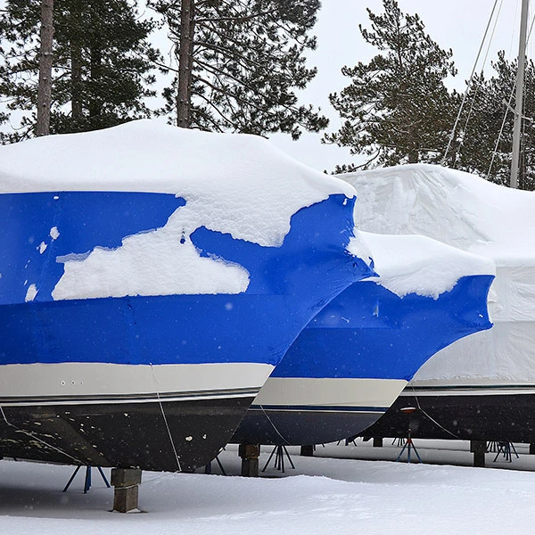Boats wrapped in shrink wrap outside covered in snow