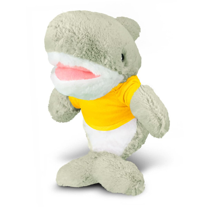 A plush shark toy in pale green with a white belly and a yellow T-shirt, featuring a brand logo.