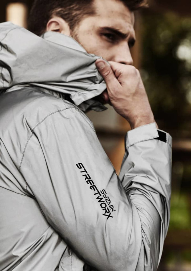 A reflective grey waterproof jacket with a logo, featuring a close-up of a model wearing it.