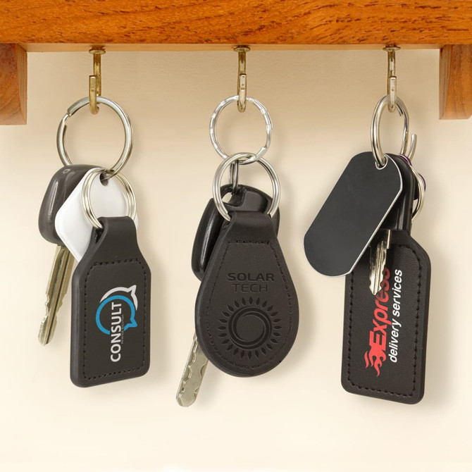 A rectangular black leather key ring with a logo, attached to a metal keychain among other keys.