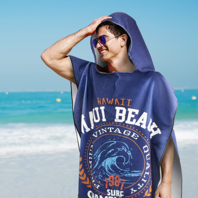 A navy blue adult hooded towel with a logo, displayed against a beach backdrop.