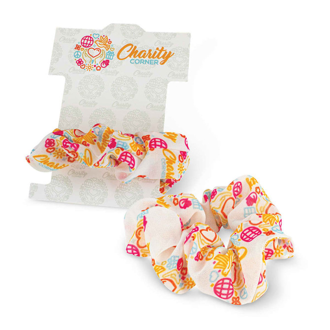A set of two colourful floral hair scrunchies displayed on a card featuring a logo.