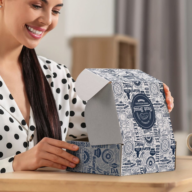 A woman is holding a blue and white die cut box with a locking lid, featuring various printed designs and a logo.
