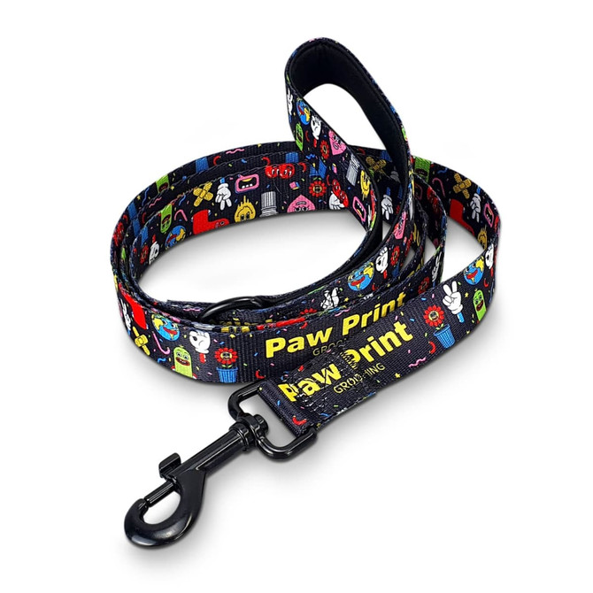 A dog leash featuring a vibrant pattern of cartoonish designs, primarily in black with colourful prints and a clip attachment.