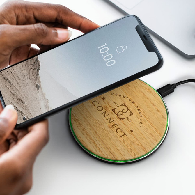 A bamboo wireless charger with a black base and a smartphone being placed on it, featuring a logo.