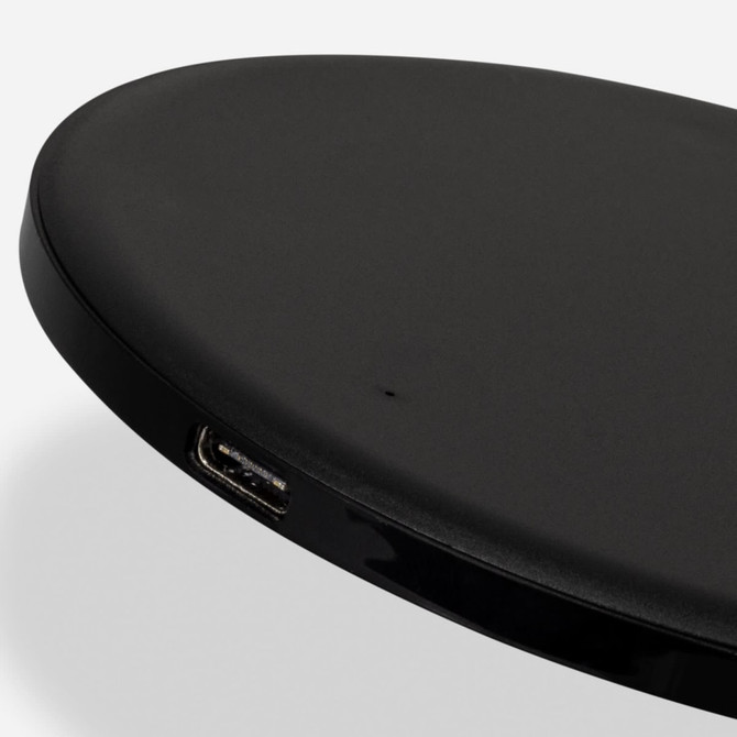 A wireless fast charger in black with a smooth, oval design and a visible USB port.