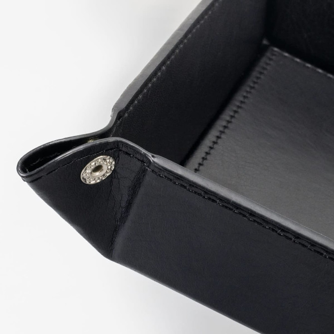 A black leather valet tray with stitched detailing and decorative fasteners at the corners.