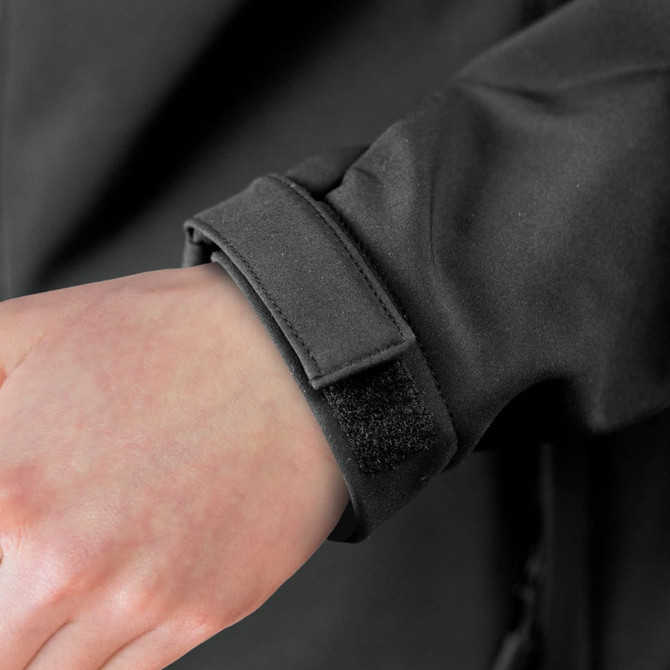 A close-up of a black soft shell jacket cuff with a Velcro strap. The fabric appears smooth and sleek.