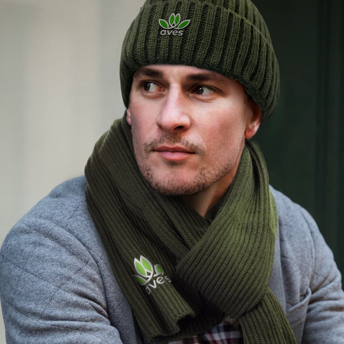 A green beanie and matching scarf set displayed on a model, featuring a logo on both items.