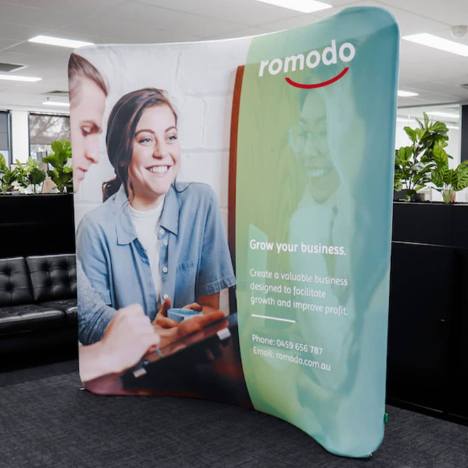 A small curved stretch media wall in green and white featuring images of people and branding elements.