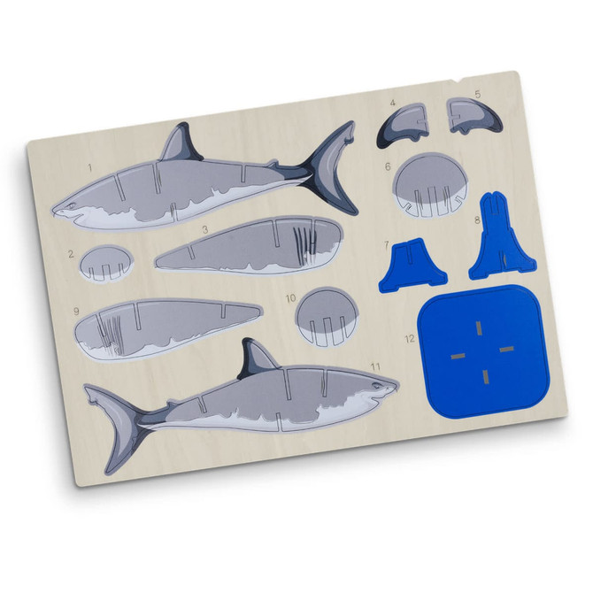 A wooden puzzle model of a shark, featuring grey and blue pieces on a light wooden base.